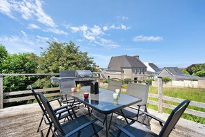Eine Terrasse mit Tisch, Stühlen, einem Grill und Blick auf Häuser im Hintergrund.
