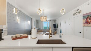 Eine moderne Küche mit Kochinsel, Pendelleuchten und Blick auf einen Balkon.