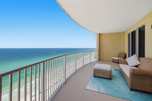 Ein Balkon mit Blick auf das Meer, eine Korbsitzgruppe und ein kleiner Tisch.
