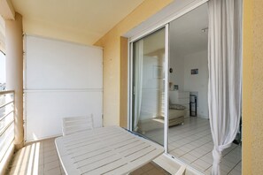 A balcony with a table and chairs, a sliding glass door to a living area, and a whiteboard on the wall. - Studio 'Port et Plage' with Sea View (La Turballe)