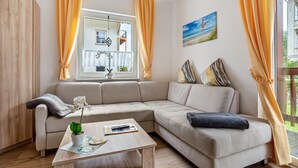 Una sala de estar moderna con un sofá color crema, una mesa de centro y una ventana con cortinas.