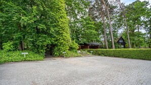 Un camino pavimentado que conduce a un edificio rodeado de exuberante vegetación y árboles.