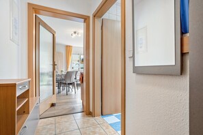 Ein Flur mit einer Holztür, einem kleinen Schrank und einem Fliesenboden.