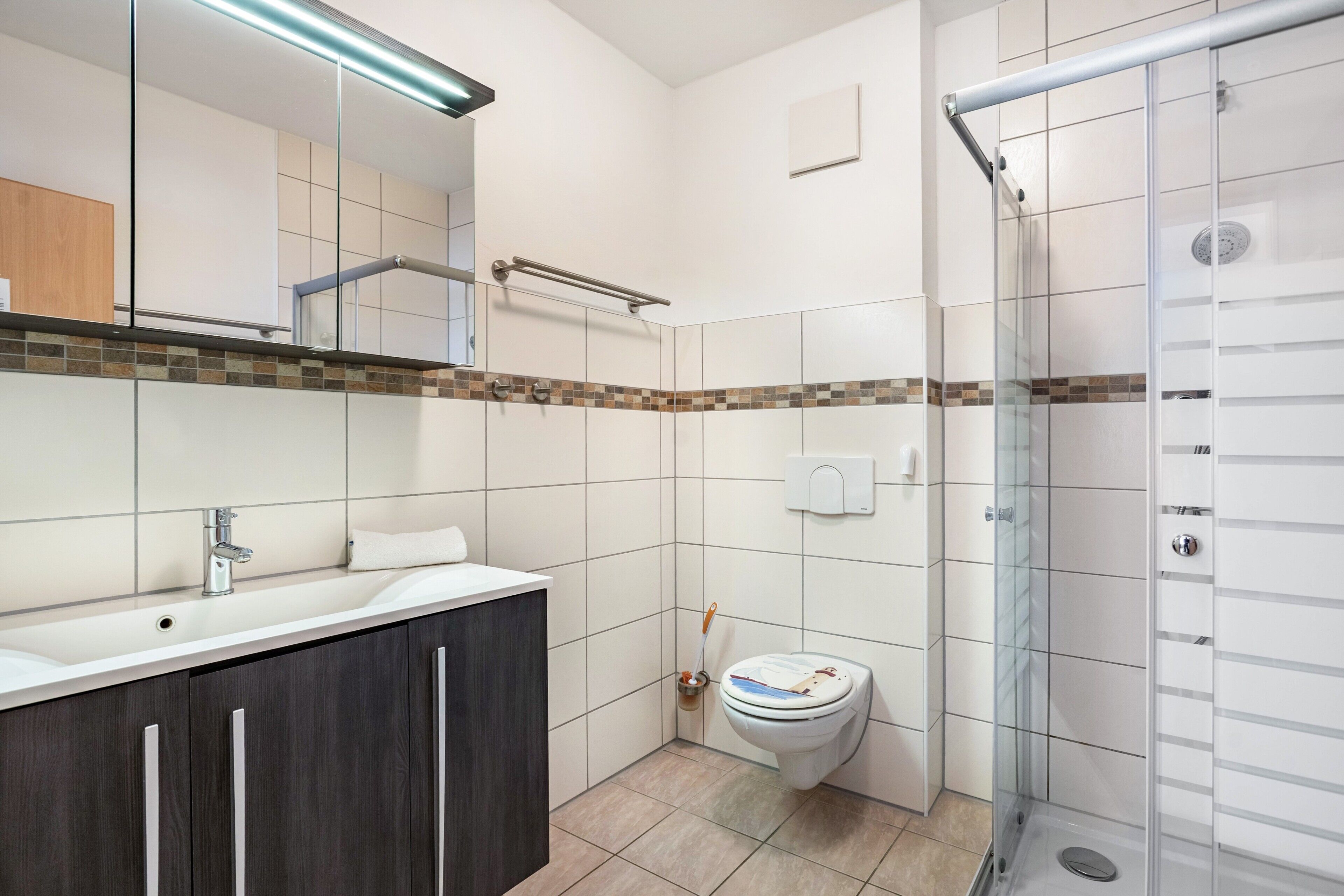 A modern bathroom with a shower, toilet, and sink.