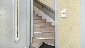 Una escala amb barana, una porta amb finestreta i un interruptor de llum fixat a la paret.