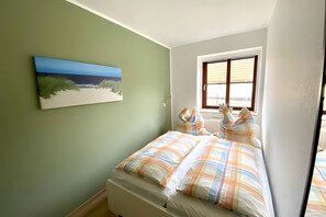 Ein Schlafzimmer mit einem Bett, einem Fenster und einem Bild an der Wand.