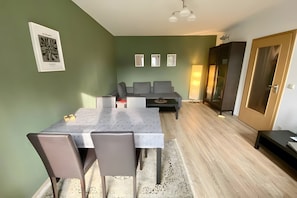 Ein Essbereich mit Tisch, Stühlen, einer Couch, einem Schrank und einer Tür.