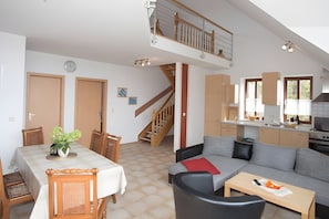 Een ruime woonkamer met een eettafel, bank en keuken.