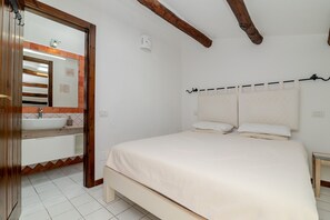 A bedroom with a large bed, a bedside table, a mirror, a bathroom with a sink and a towel rack. - Apartment 'Casa Baia Del Faro' with Sea View, Private Terrace and Air Conditioning (Palau)