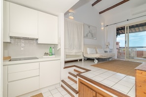 Een moderne keuken met witte kasten, een aanrecht en uitzicht op een balkon.