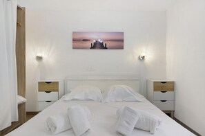 Une chambre d’hôtel avec un lit, deux tables de chevet, un tableau au-dessus du lit et une vue sur une étendue d’eau.