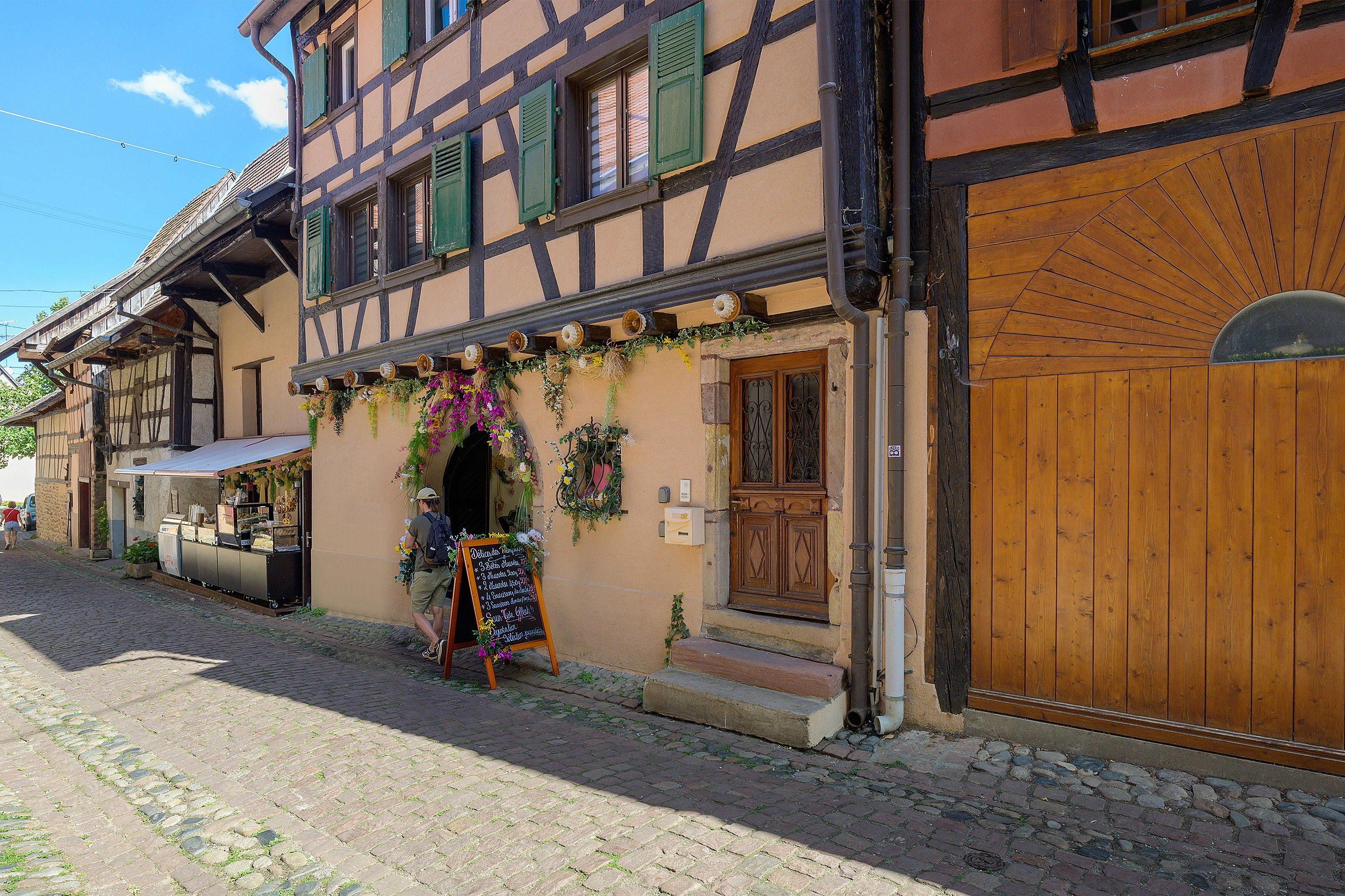 Un bâtiment traditionnel à colombages, doté d’une porte en bois et d’une enseigne devant l’entrée.