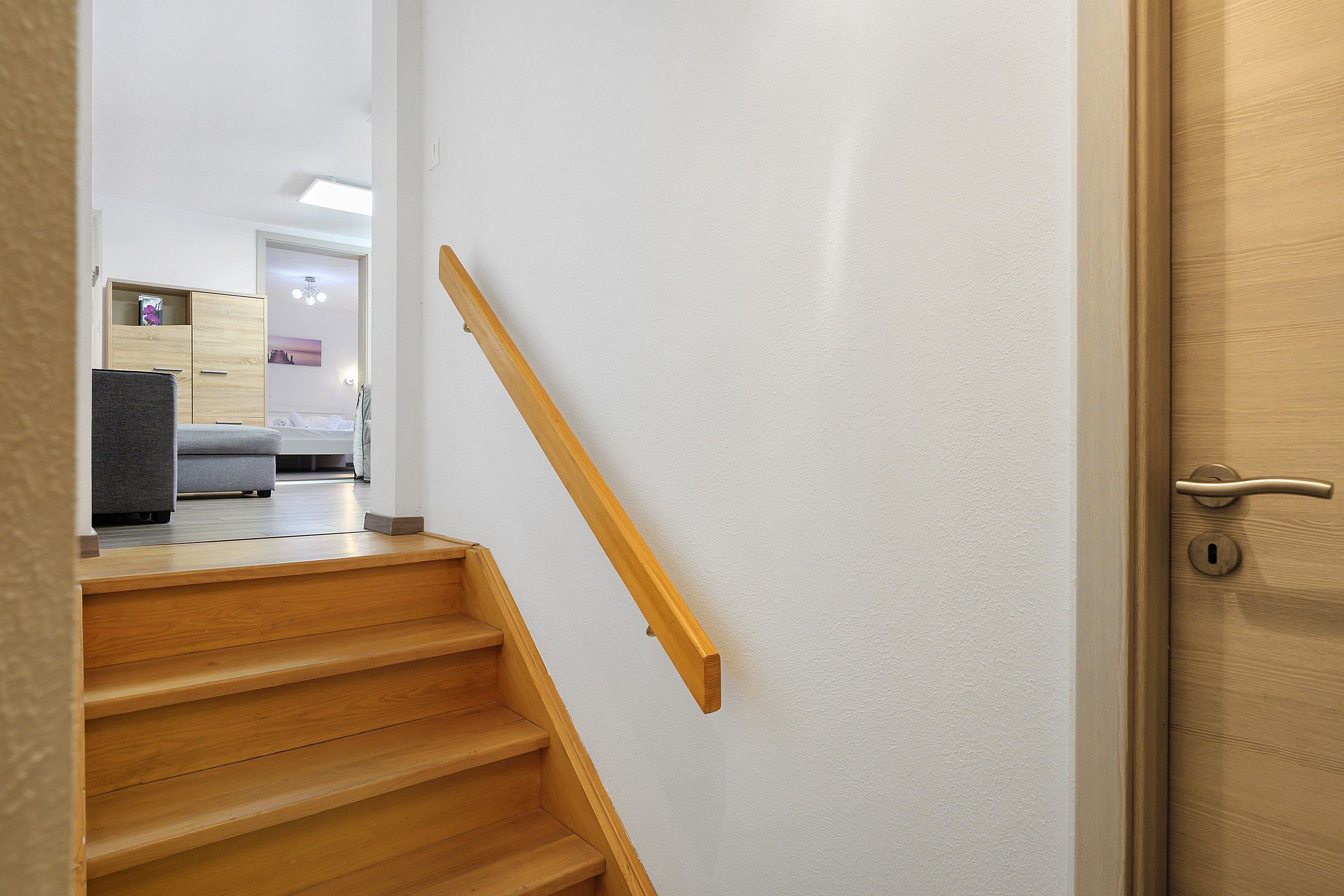 Eine Holztreppe führt zu einem Zimmer mit einem Bett und einem Nachttisch.