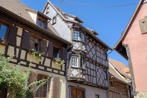 Ein traditionelles Fachwerkhäuschen mit einem steilen Satteldach, Dachfenstern und einer Holztür.