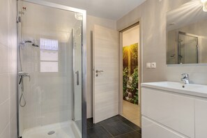 A modern bathroom with a glass shower enclosure, a sink with a mirror, and a door with a nature-themed wallpaper. - Le Zen d'Eguisheim – A Timeless Escape (Eguisheim)