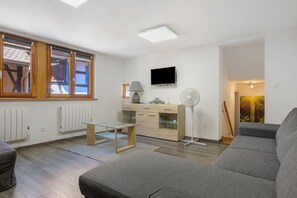 Un salon moderne avec un canapé, une table basse en verre, un téléviseur et un radiateur.