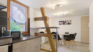 A modern kitchen with a microwave, a wooden beam structure, and a dining area with chairs and a table.