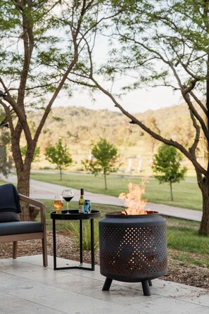 An outdoor seating area with a fire feature, a table with drinks, and a chair. - 'Eclipse' at Small Batch (Budgee Budgee)