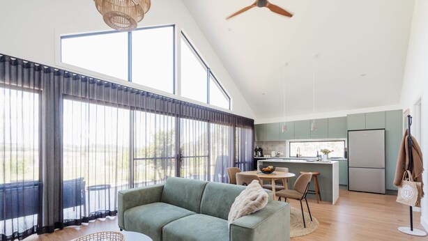 A spacious living area with a sofa, a dining table, and a kitchen in the background. - 'Eclipse' at Small Batch (Budgee Budgee)