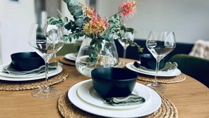 A dining table set with clear glass wine glasses, black bowls, and a centerpiece of flowers. - 'Eclipse' at Small Batch (Budgee Budgee)