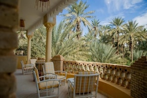 A covered outdoor seating area with wicker chairs and a brick wall. - Dar Rouissi (Tozeur)