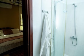 A hotel room with a bed, a shower, and a towel rack.