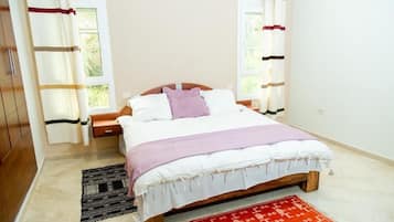 A bedroom with a bed, nightstand, and a window with curtains.