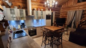 Una cocina moderna con comedor, techo de madera y una lámpara de araña.