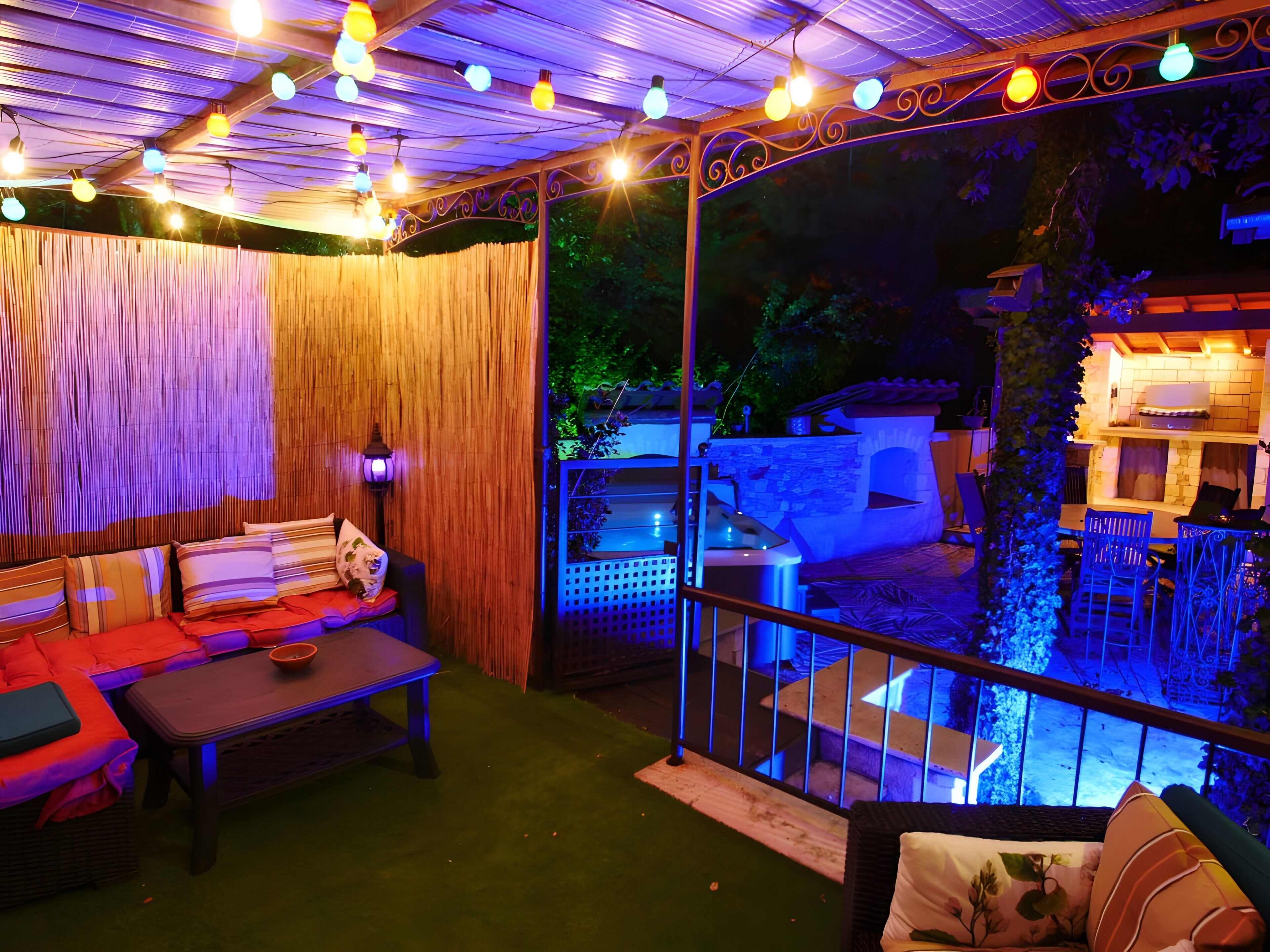 Un patio al aire libre con un banco de madera, una mesa y una barandilla con vistas a un jardín.