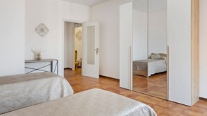 Een slaapkamer met een bed, een kledingkast en een bureau met een vaas.