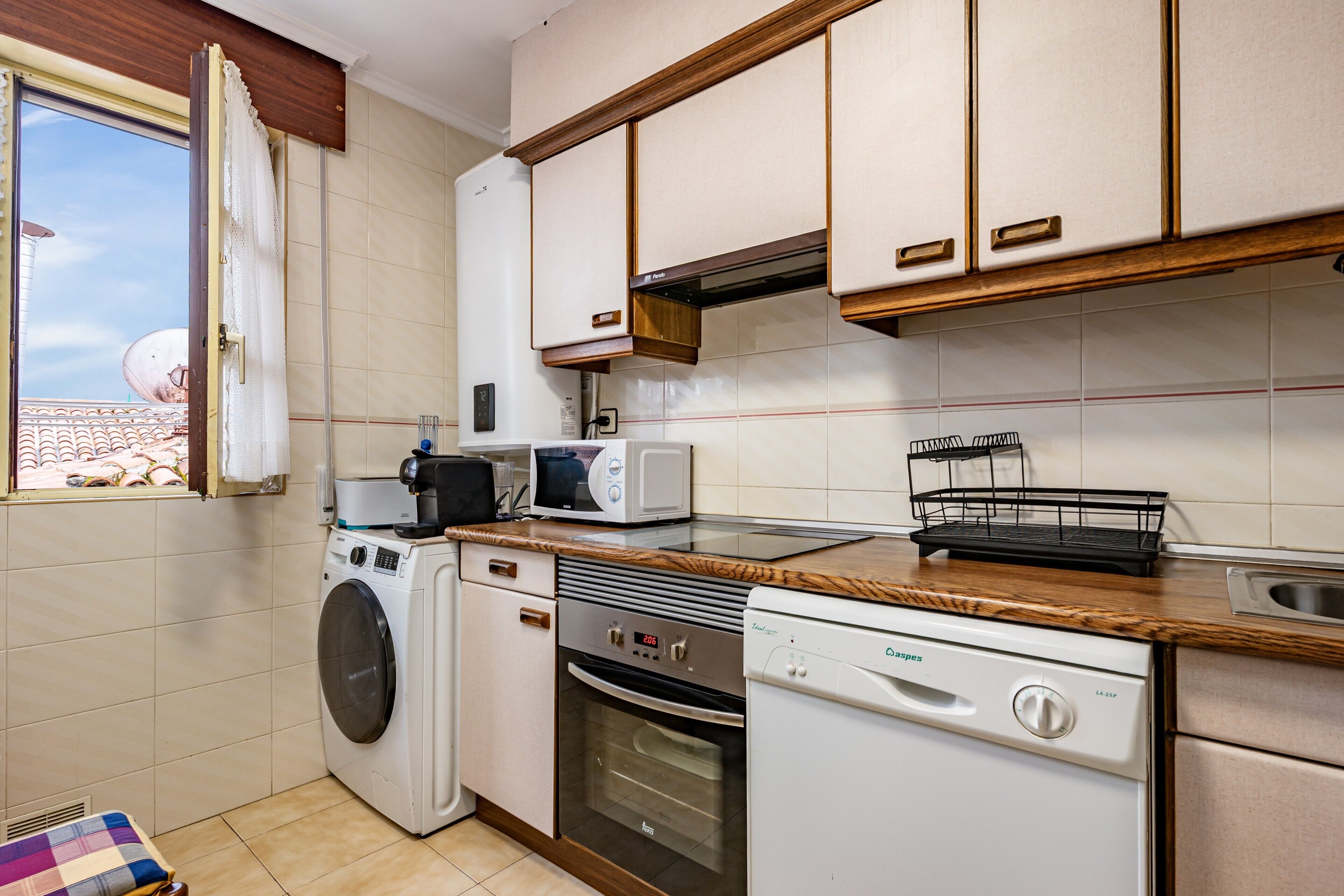 A compact kitchen with a washing machine, dishwasher, oven, and microwave.