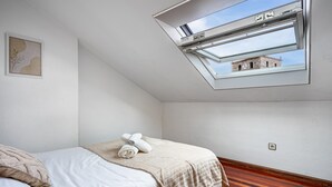 A bedroom with a skylight, a bed with a beige blanket, a wooden floor, and a framed picture on the wall. - Apartment 'Centro Y Mar En Llanes' with Sea View and Wi-Fi (Llanes)