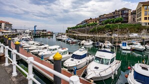 A marina with multiple boats docked, a bridge in the background, and buildings along the waterfront. - Apartment 'Centro Y Mar En Llanes' with Sea View and Wi-Fi (Llanes)