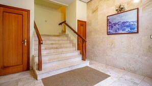 A staircase with wooden handrails, a beige carpet, and a painting of a cityscape on the wall. - Apartment 'Centro Y Mar En Llanes' with Sea View and Wi-Fi (Llanes)
