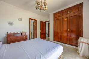 Ein Schlafzimmer mit einem großen Bett, einem Holzschrank und einer Pendelleuchte.
