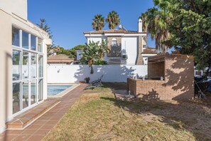 A residential property with a swimming pool, a patio area, and a brick structure.