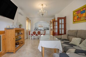 A living room with a sofa, a dining table, and a kitchen in the background. - Holiday Villa with Private Pool in Chiclana de la Frontera (Chiclana de la Frontera)