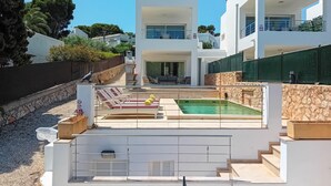 Una villa moderna con piscina, area salotto esterna e un muro in pietra.