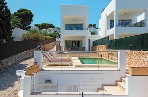 A modern villa with a swimming pool, outdoor seating, and a stone wall. - Holiday Home 'Kanavayen Tres' with Sea View, Wi-Fi and Air Conditioning (Santanyí)