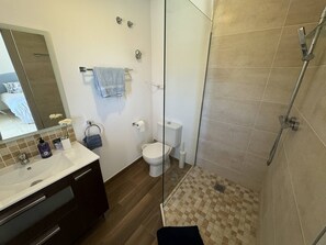 Un baño moderno con cabina de ducha de vidrio, un inodoro y un lavabo con tocador.