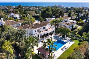 A large house with a pool, surrounded by palm trees and other greenery. - Villa in Marbella with Private Pool, Gym, and Sea Views (Marbella)