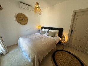 A bedroom with a bed, bedside lamps, a woven wall hanging, a door, and a rug. - Villa in Marbella with Private Pool, Gym, and Sea Views (Marbella)