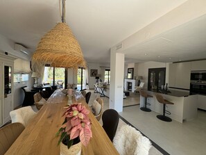 A modern kitchen with a central island, a dining area with a wooden table and chairs, and a large woven light fixture. - Villa in Marbella with Private Pool, Gym, and Sea Views (Marbella)