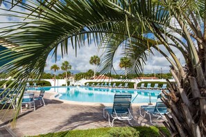 A pool area with lounge chairs and palm trees. - Ocean and racquet Club: steps to ocean, pool, tennis and pickleball (saint augustine)