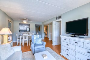 A living room with a TV, a dining area, and a kitchen. - Ocean and racquet Club: steps to ocean, pool, tennis and pickleball (saint augustine)