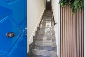 Una escalera con una puerta azul a la izquierda y un panel de madera en la derecha.