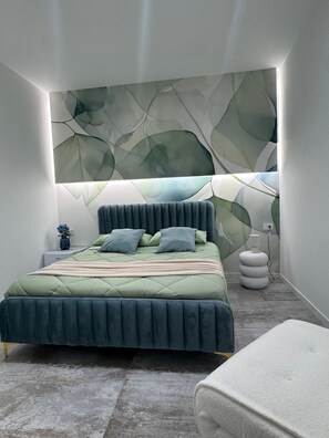 A modern bedroom with a bed, bedside tables, a wall-mounted light, and a decorative wall panel.