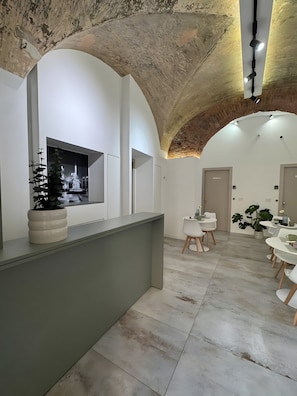 A modern interior with a reception desk, seating area, and a large arched ceiling.