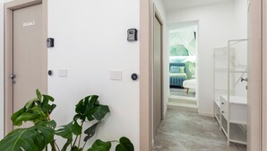 A hallway with a door labeled 'ROOM 2', a wall-mounted intercom, and a plant. - Neg Naumachia Rooms - Triple Room 3 (Catania)