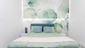 A bedroom with a bed, pillows, a nightstand, and a wall with a leaf pattern. - Neg Naumachia Rooms - Triple Room 3 (Catania)